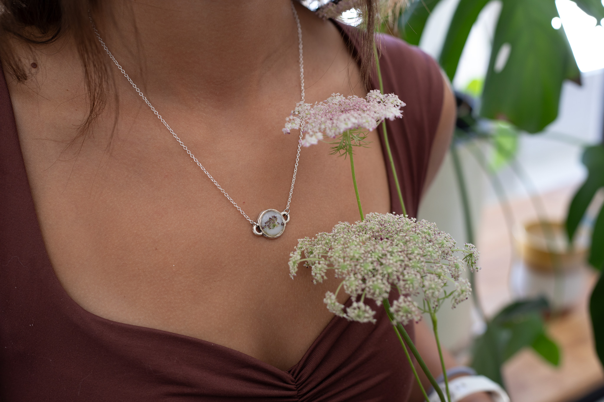 Queen Anne’s Lace necklace worn with a plum top beside fresh flowers